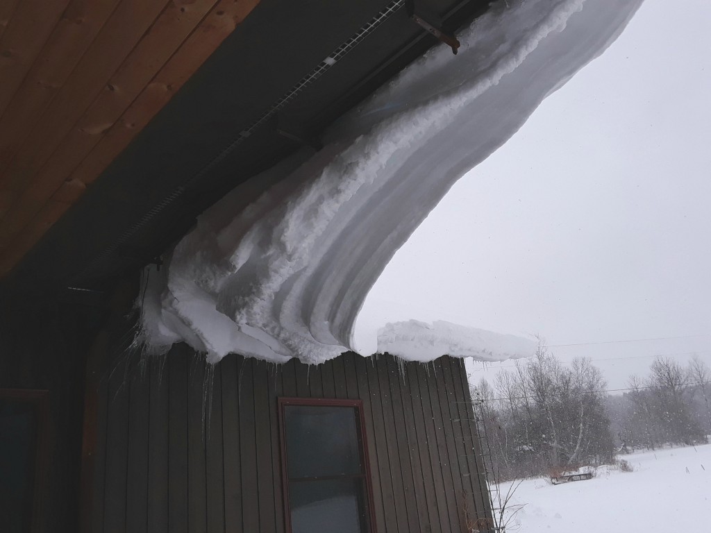 the slope of the roof is such that snow neither accumulates nor slides right off. Instead, it forms a little glacier and creeps over the edge.  At the corner, 2 flows collide and constipate the flow. I poke it with a pitchfork once in awhile, and a ton of snow comes crashing down. 